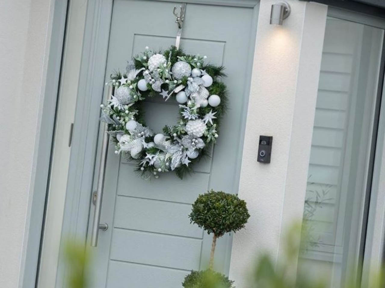 light green composite door with a wreath hanging on it